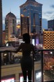 A woman standing on a balcony looking out over a city.