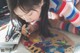 A little girl is painting on a wooden board.