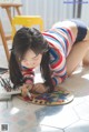 A young girl laying on the floor drawing with colored pencils.