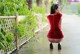 A woman in a red dress crouching down on a sidewalk.