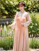 A woman in a pink dress standing in a garden.