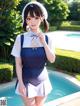 A woman in a maid outfit standing next to a swimming pool.