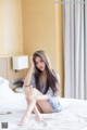 A woman sitting on a bed in a hotel room.