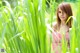 A woman in a red and white striped dress standing in tall grass.