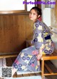 A woman in a kimono sitting on a wooden bench.