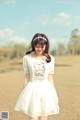 A woman in a white dress standing in a field.