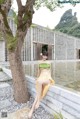 A woman sitting on a stone wall next to a tree.