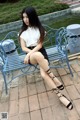 A woman sitting on a blue bench next to a pond.