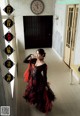 A woman in a black and red dress standing in a hallway.