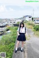 A woman in a school uniform standing on the side of a road.