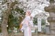 A woman in a kimono holding a basket in front of a tree.