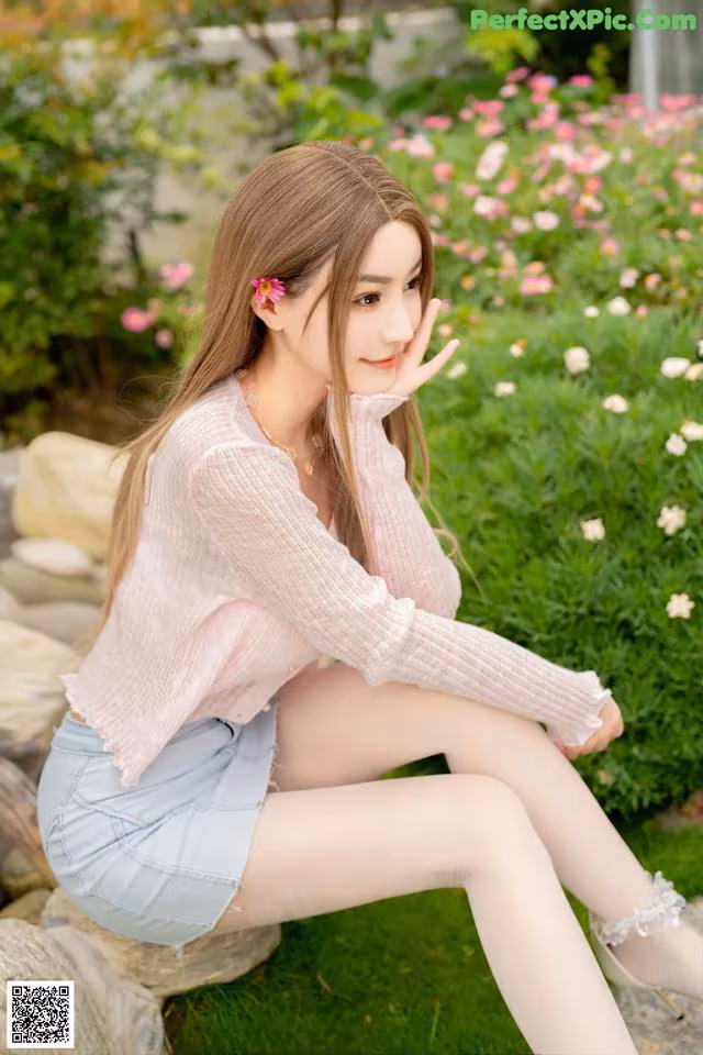 A woman sitting on a rock in a garden.