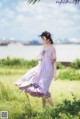 A woman in a purple dress is walking in a field.