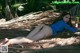 A woman in a blue bathing suit laying on a palm tree.