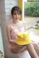 a woman sitting on a window sill wearing a yellow hat