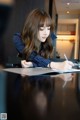 A woman sitting at a table writing on a piece of paper.