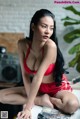 A woman in a red lingerie sitting on a table.