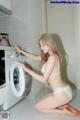 A woman in a white lingerie is putting something in a washing machine.