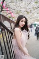 A woman in a pink dress standing next to a fence.