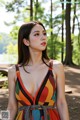 A woman in a colorful dress standing in the woods.