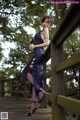 A woman in a purple dress standing on a wooden bridge.