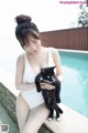 A woman in a white bathing suit holding a black and white cat.