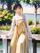 A woman in a yellow and white dress standing on a bridge.