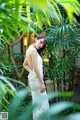 A woman in a white dress standing in front of a tree.