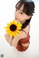 A woman holding a sunflower in her hand. 