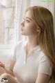 A woman sitting on a window sill looking out the window.