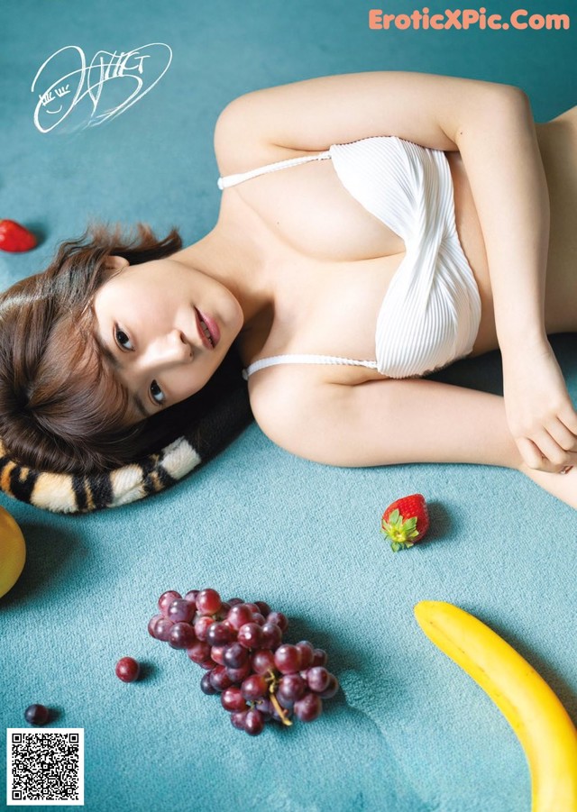 A woman laying on the ground next to a bunch of fruit.