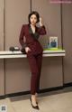 A woman in a red suit standing in front of a counter.