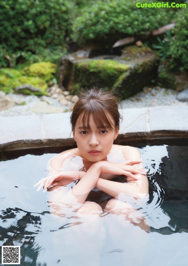 A woman sitting in a hot tub with her hands on her knees.