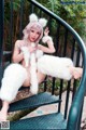 A woman in a white furry outfit sitting on a set of stairs.