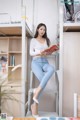 A woman sitting on top of a bunk bed reading a book.