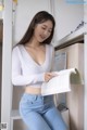 a woman in jeans and a white sweater is reading a book