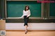 A woman standing in front of a blackboard in a classroom.