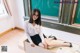 A woman sitting on top of a desk in front of a blackboard.