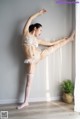 A woman in a white lingerie and stockings leaning against a wall.