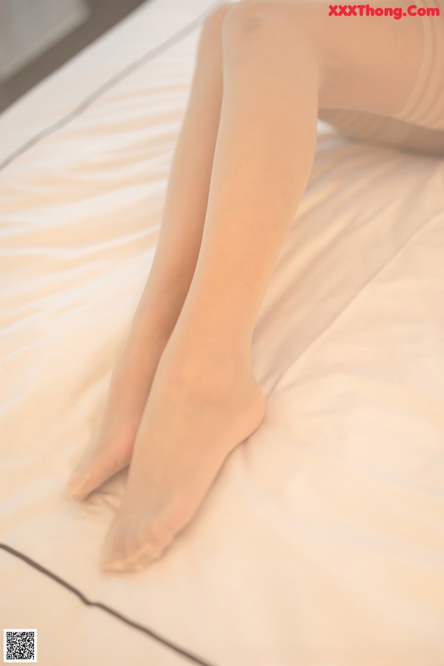 A woman is sitting on a bed with her legs crossed.